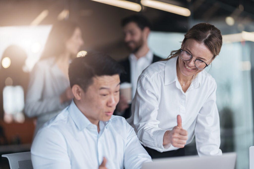 Smiling female employee discussing online project, showing presentation to skilled team leader